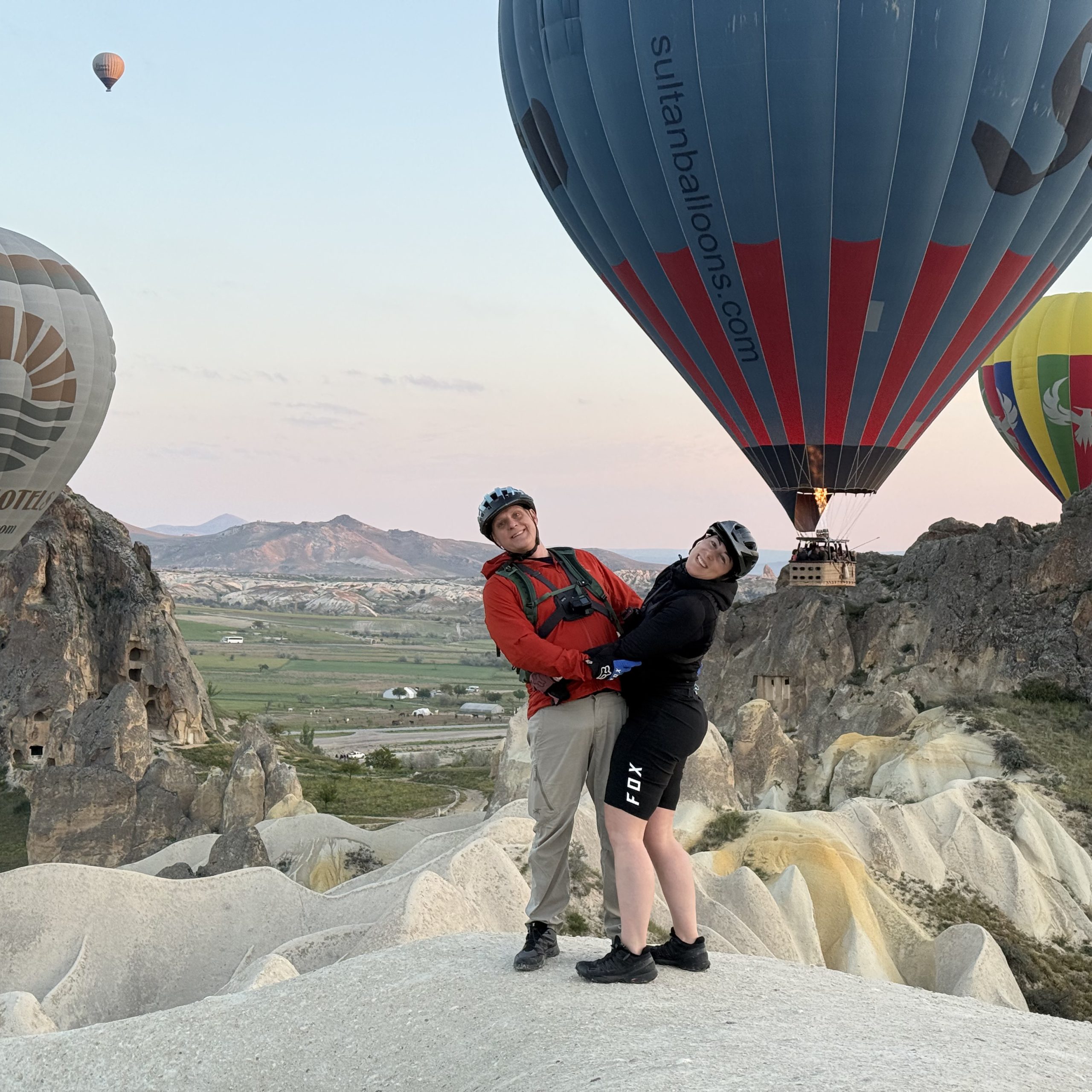 Couple posing in front of hot air balloons during a bike tour in Cappadocia