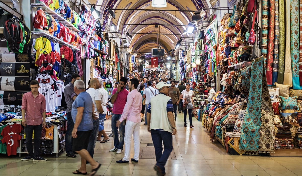 Shoppers browsing colorful textile and clothing stalls inside Istanbul’s Grand Bazaar