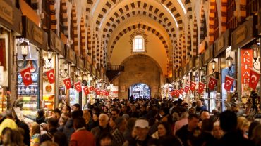 Busy shopping scene inside Istanbul’s Grand Bazaar with Turkish flags and vaulted architecture