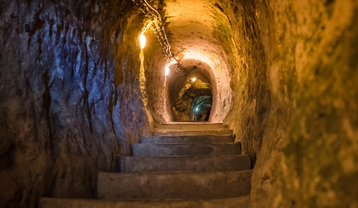A stone staircase leading through a narrow tunnel inside Cappadocia’s underground city. The softly glowing lights along the rocky walls emphasize the ancient craftsmanship and the mysterious, historic ambiance of this hidden world.