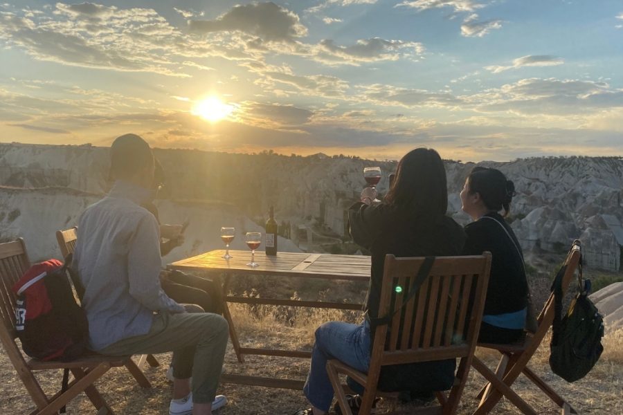 Guests enjoying a private sunset wine tasting in Cappadocia overlooking fairy chimney valleys with glasses of local red wine.